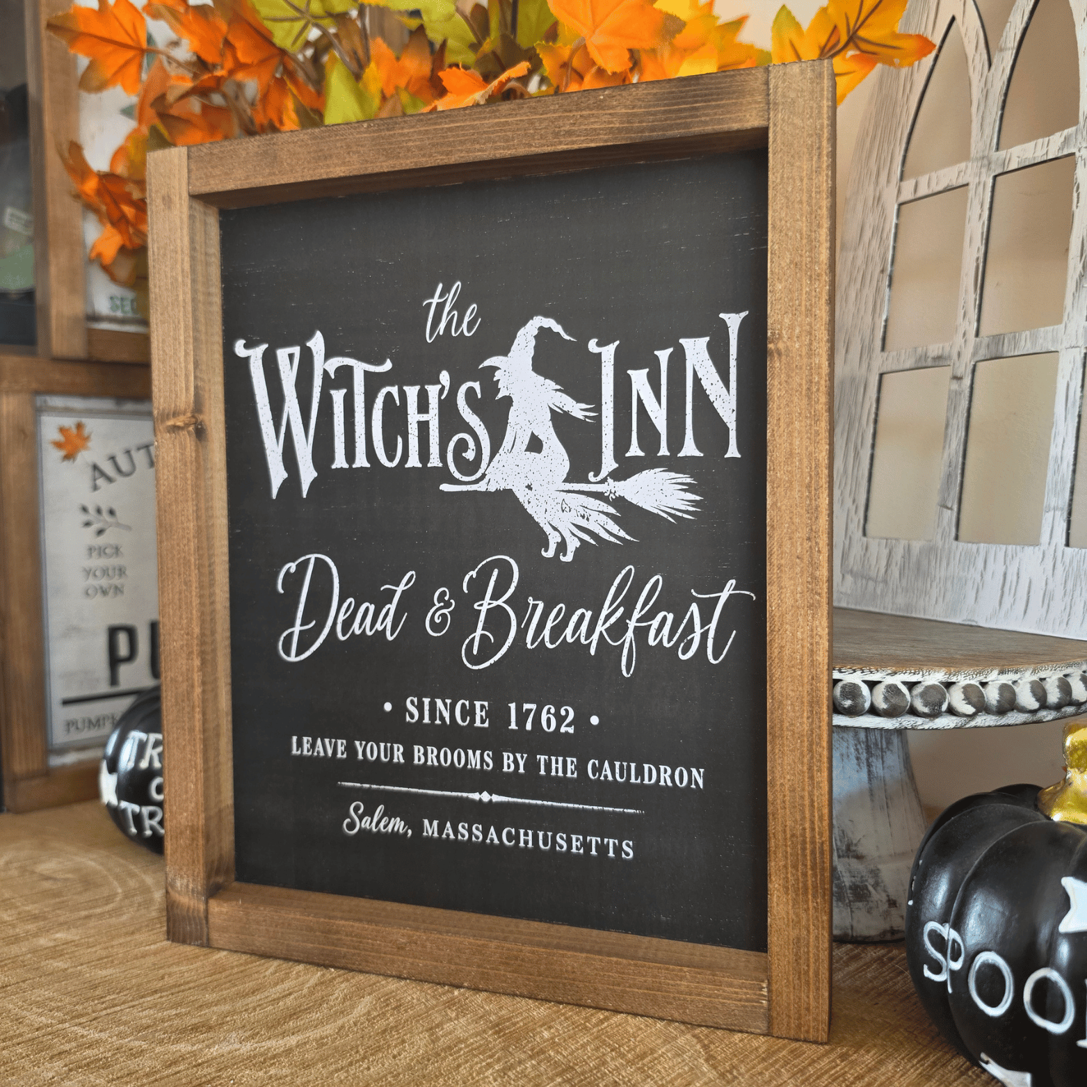 Cadre sign farmhouse The Witch’s Inn noir avec sorcière sur un balai